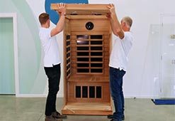 Deux hommes assemblent un sauna infrarouge 1 place, installation facile