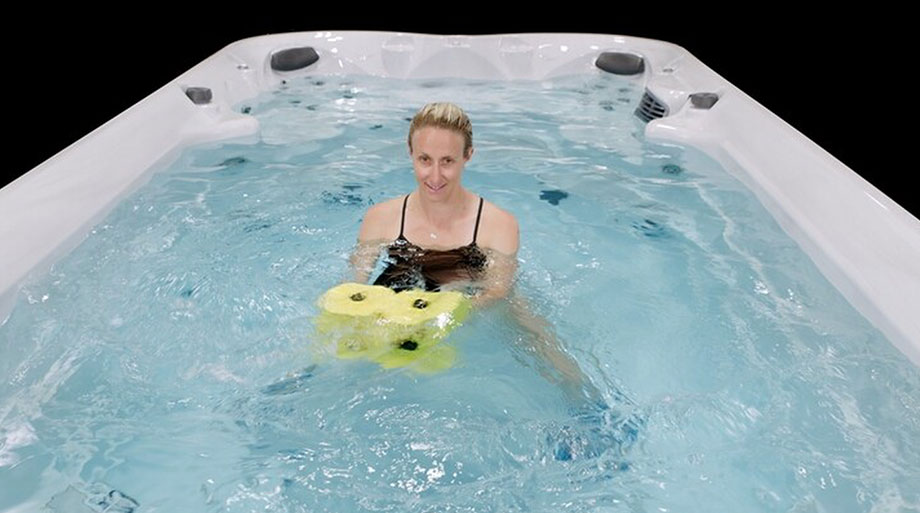 Poussées frontales avec haltère aquatique dans un spa de nage Jacuzzi® Séance d’aquagym dans un jacuzzi de nage avec haltère aquatique et chevillères